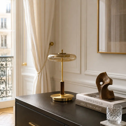 Lampe à poser Lentis en verre fumé et laiton posée sur une commode noire dans un intérieur haussmannien