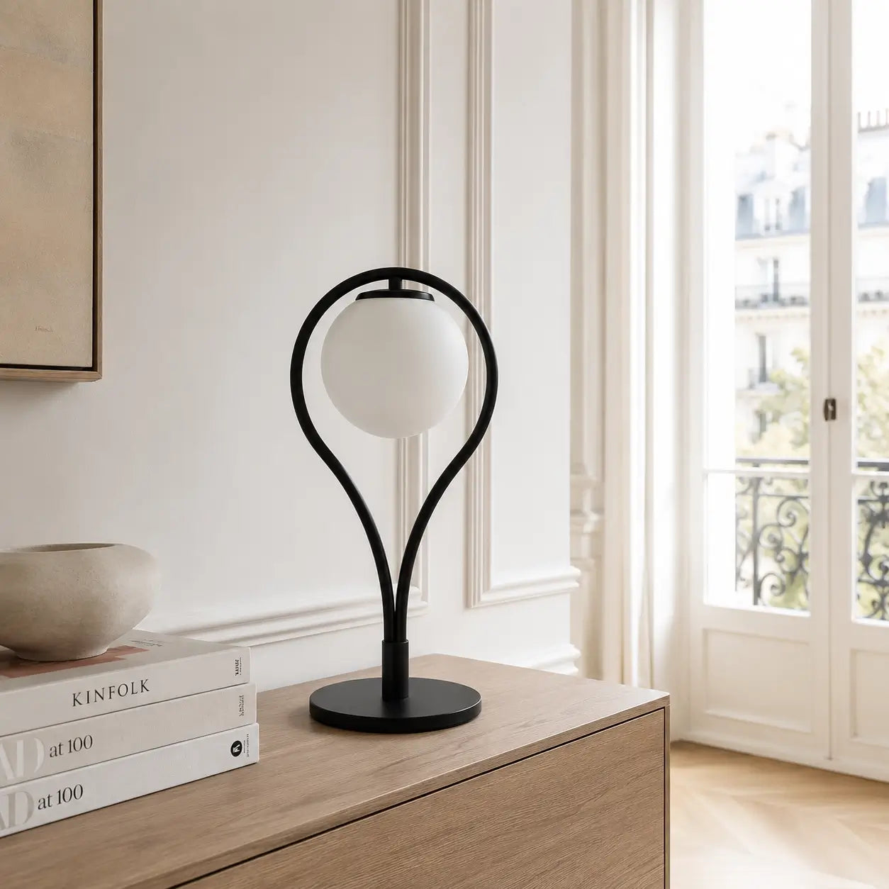 Lampe de bureau Halos à anneau noir et globe opalin posée sur un buffet en chêne dans un intérieur haussmannien lumineux