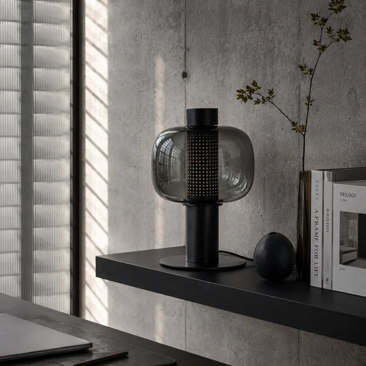 Lampe de bureau Astrum posée dans un intérieur béton brut avec jeux de lumière naturelle