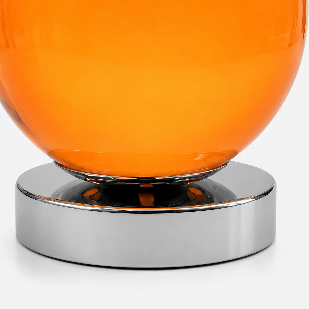 Détail de la lampe Ignis : jonction entre le globe en verre soufflé orange et la base en métal chromé poli