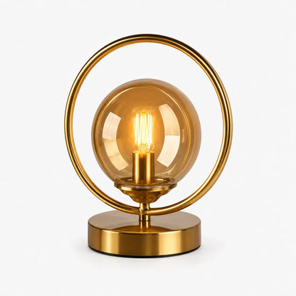 Lampe de bureau en laiton doré à globe en verre ambré et anneau circulaire, modèle Orbis, allumée sur fond clair