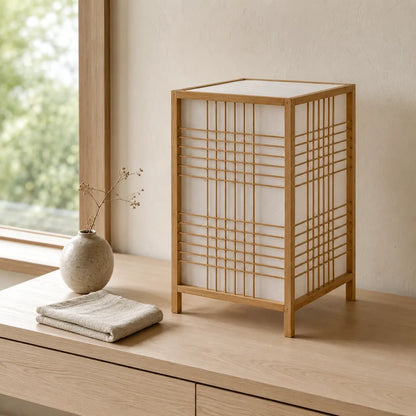 Lampe lanterne Tessera en bambou posée sur un buffet en chêne près d'une fenêtre dans un intérieur japandi
