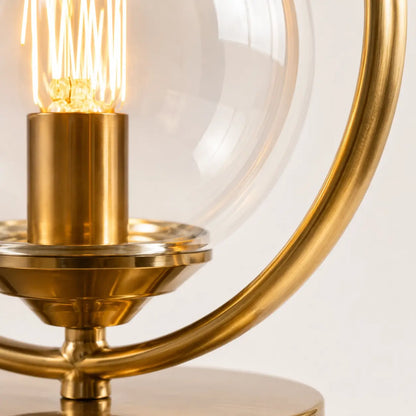 Détail de la lampe Orbis : anneau en laiton brossé, douille dorée et globe en verre transparent au filament allumé