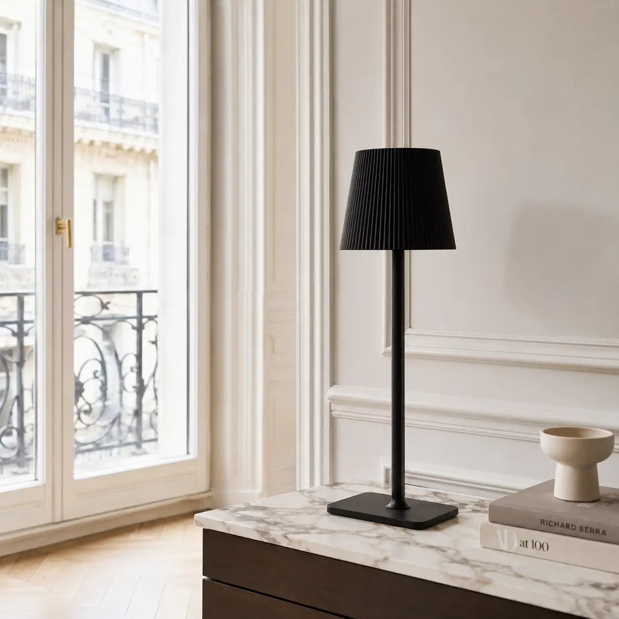 Lampe de bureau sans fil Lucerna noire posée sur une console en marbre dans un intérieur haussmannien lumineux