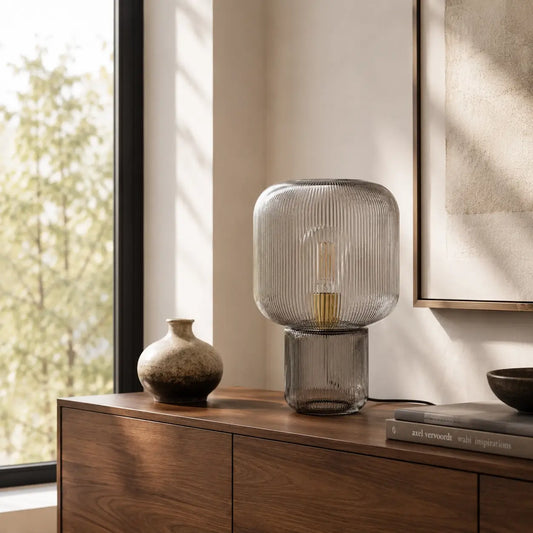 Lampe de bureau verre Stria posée sur un meuble bois dans un intérieur lumineux